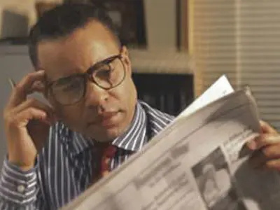 A man sitting at a table reading a newspaper.