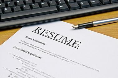A resume is sitting on top of the table next to a keyboard.