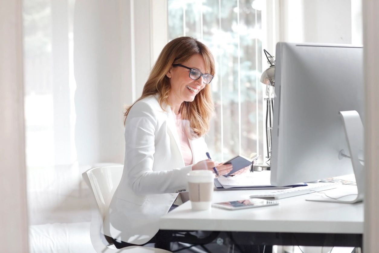 A woman sitting at her desk with a cup of coffee.