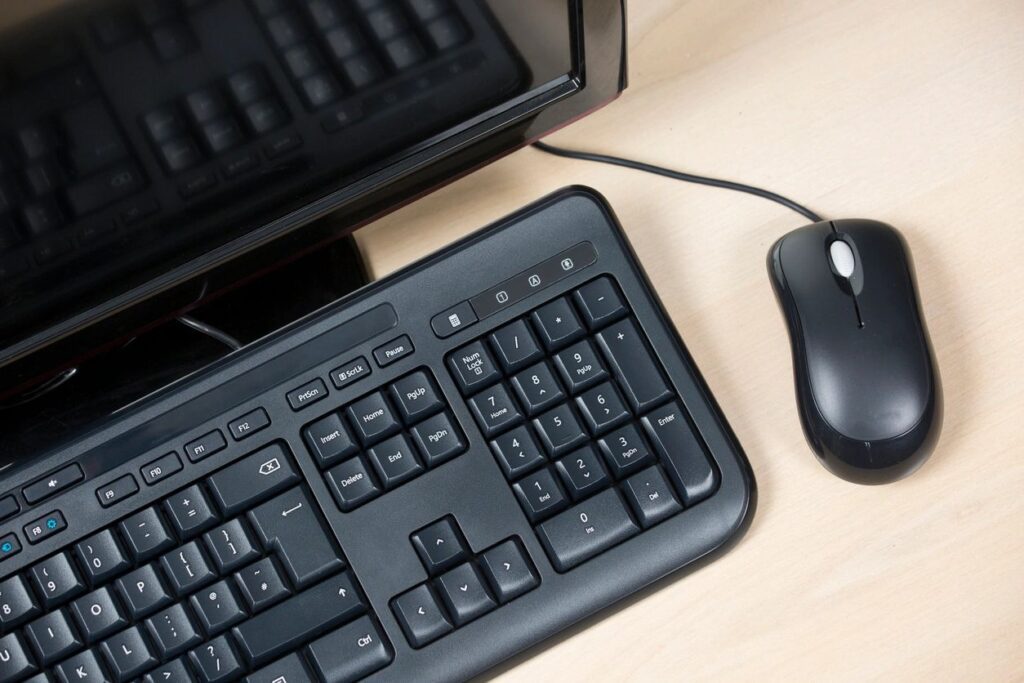 A computer keyboard and mouse on top of a desk.