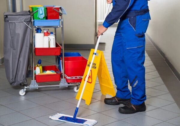 A man in blue overalls mopping the floor.